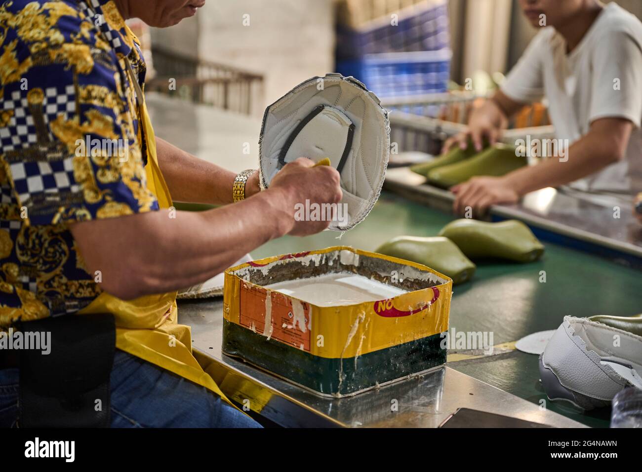 Worker doing his task in shoes production line in Chinese shoes factory Stock Photo