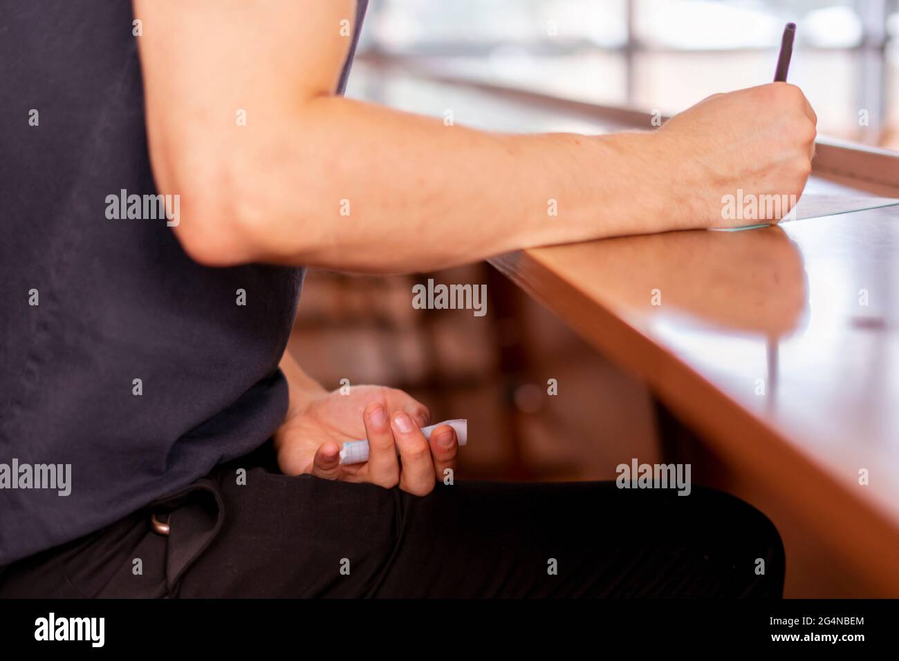 close up person sitting in lecture hall and cheating while passing the exam Stock Photo