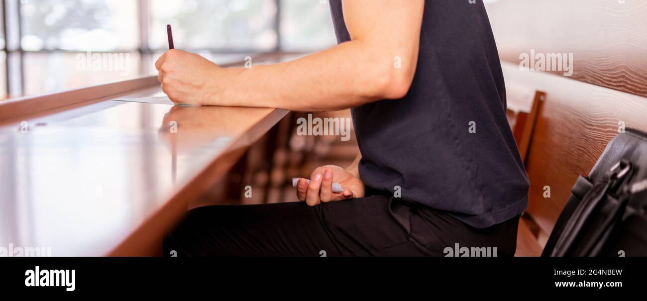 close up person sitting in lecture hall and cheating while passing the exam Stock Photo