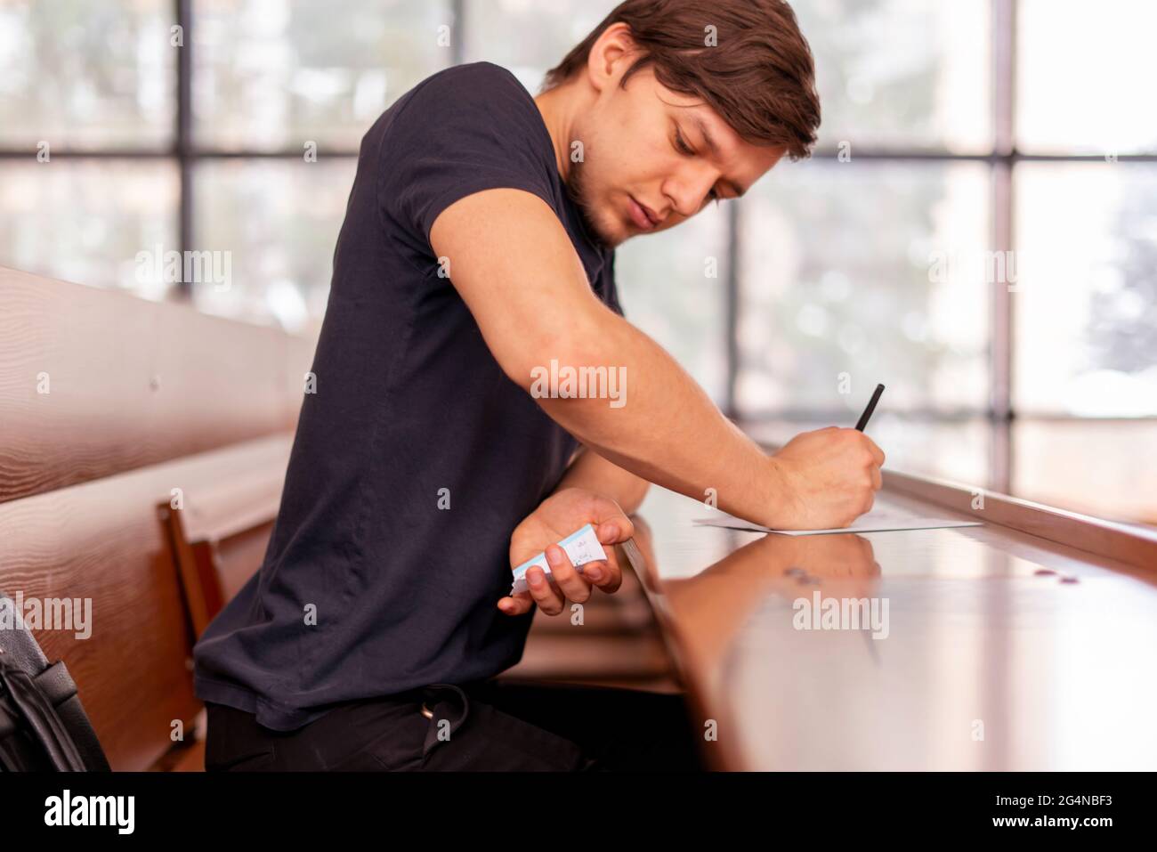 close up person sitting in lecture hall and cheating while passing the exam Stock Photo