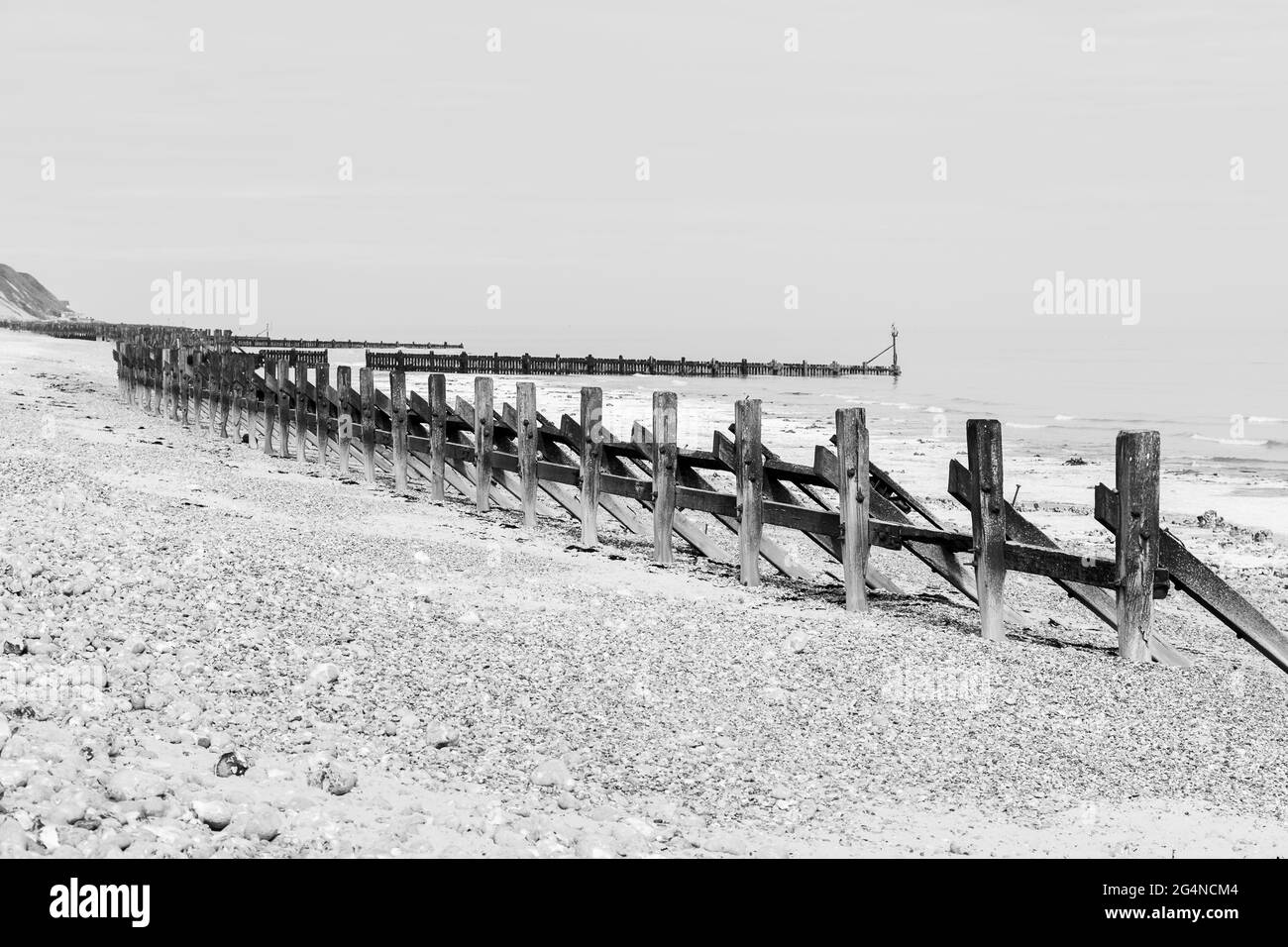 Wooden revetments at West Runton beach in black and white seen on the North Norfolk coast in June 2021. Stock Photo