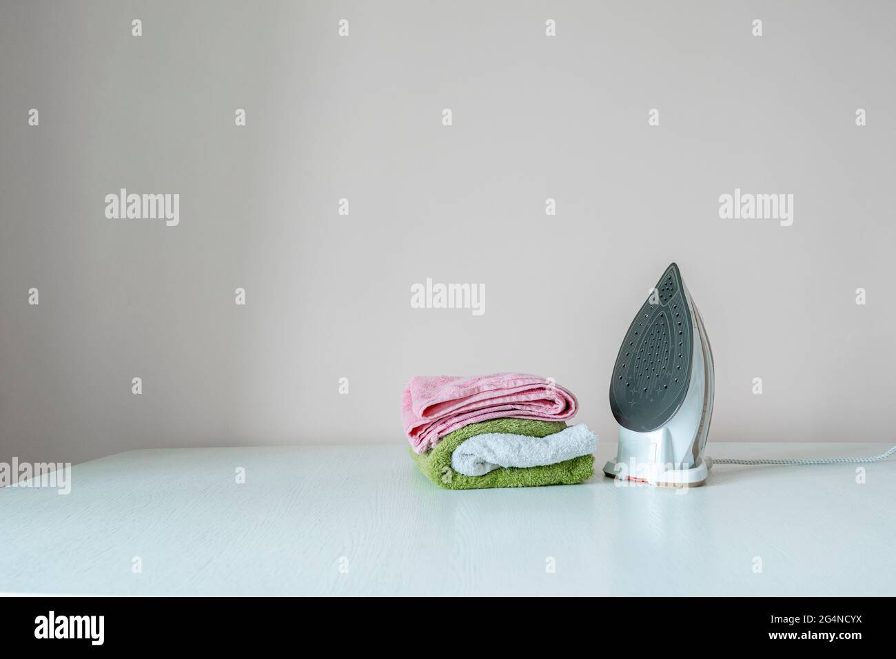 simple scene of the iron and stack of fresh clean colorful towels on