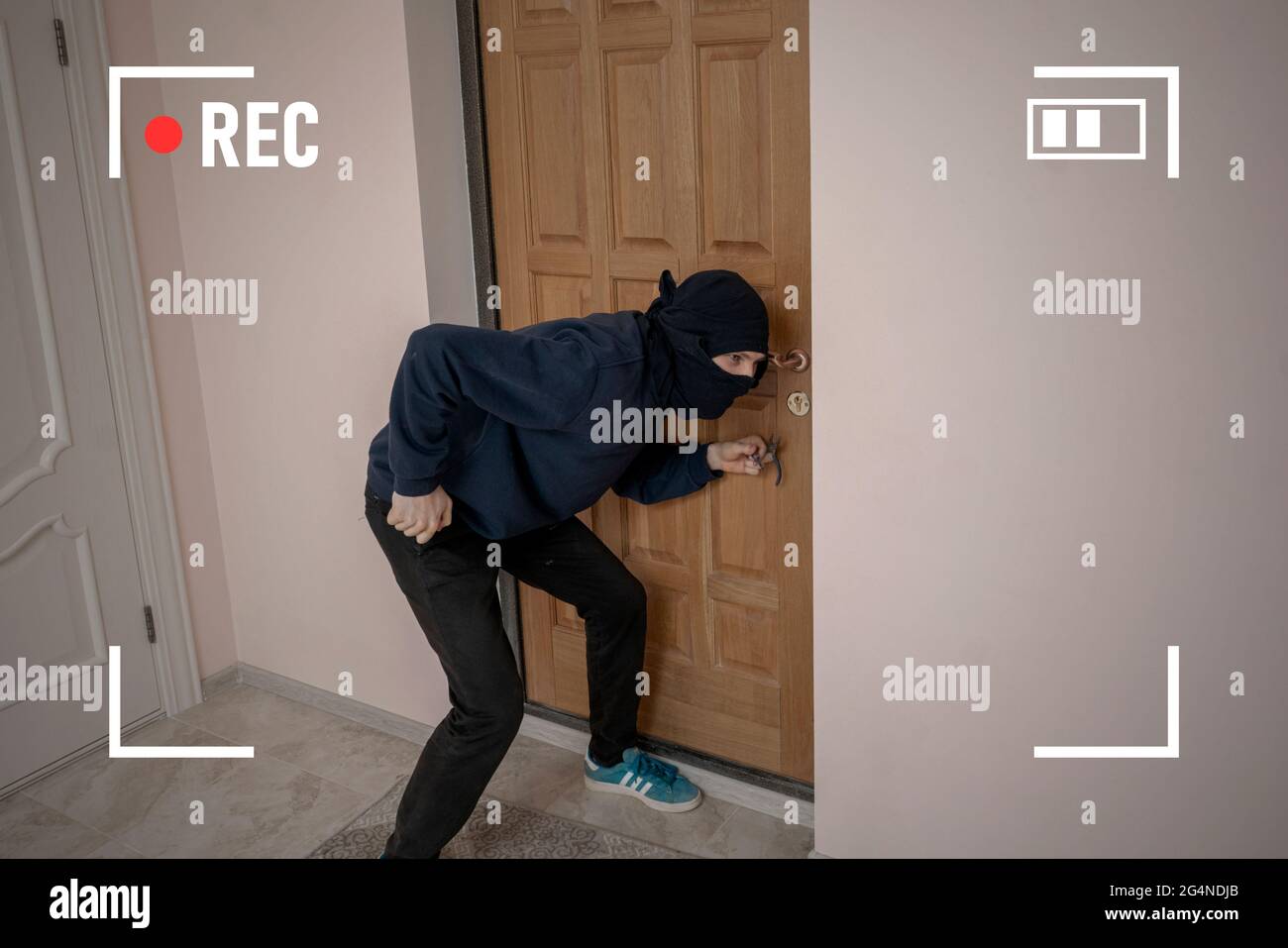 the crime burglar in black mask try to break door on house apartments, the secret cctv camera system Stock Photo