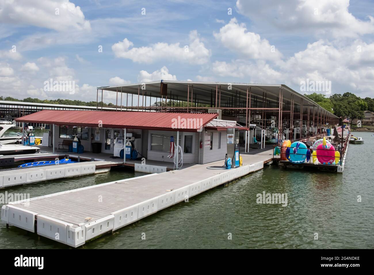 Dock and store gas station at luxury marina that has private patios for boat stalls - American flags flying and restaurant in distance Stock Photo