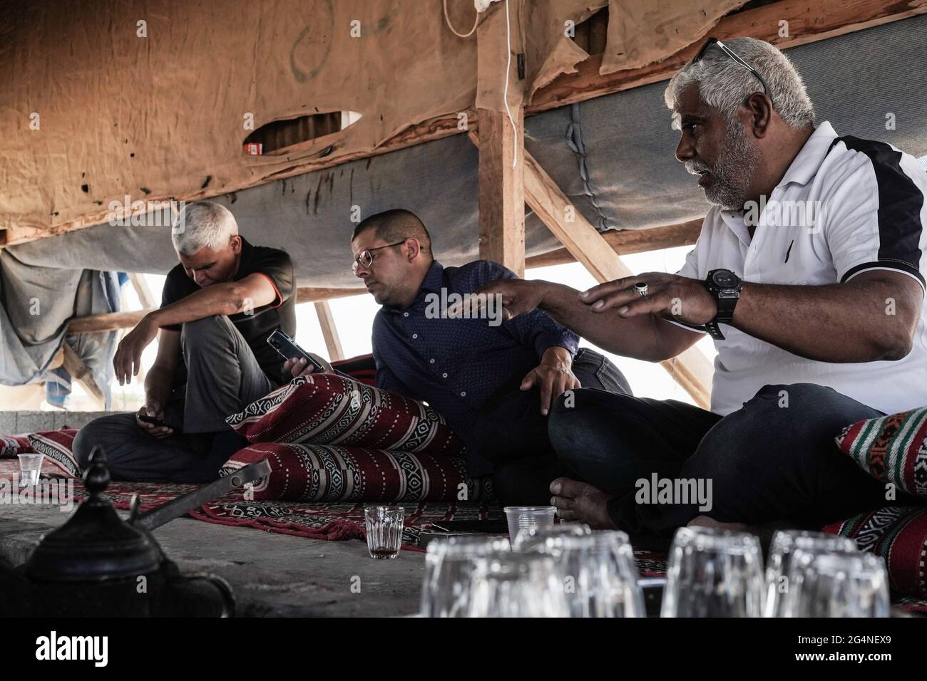 Bir Hadaj, Israel. 22nd, June 2021. SALEEM AL DANFEIRI (R), head of the local committee of Bir Hadaj, explains the uncertain future and threat of eviction under which Bedouins live in the unrecognized villages and home demolitions in the legal townships of illegal building in the visitors' tent in the Bedouin town of Bir Hadaj. The decades long political battle for the unrecognized Bedouin villages and development of those already legalized in the Israeli Negev climaxes as the new Bennett - Lapid unity government depends on supporting votes from the four Knesset seats belonging to the Raam, Un Stock Photo