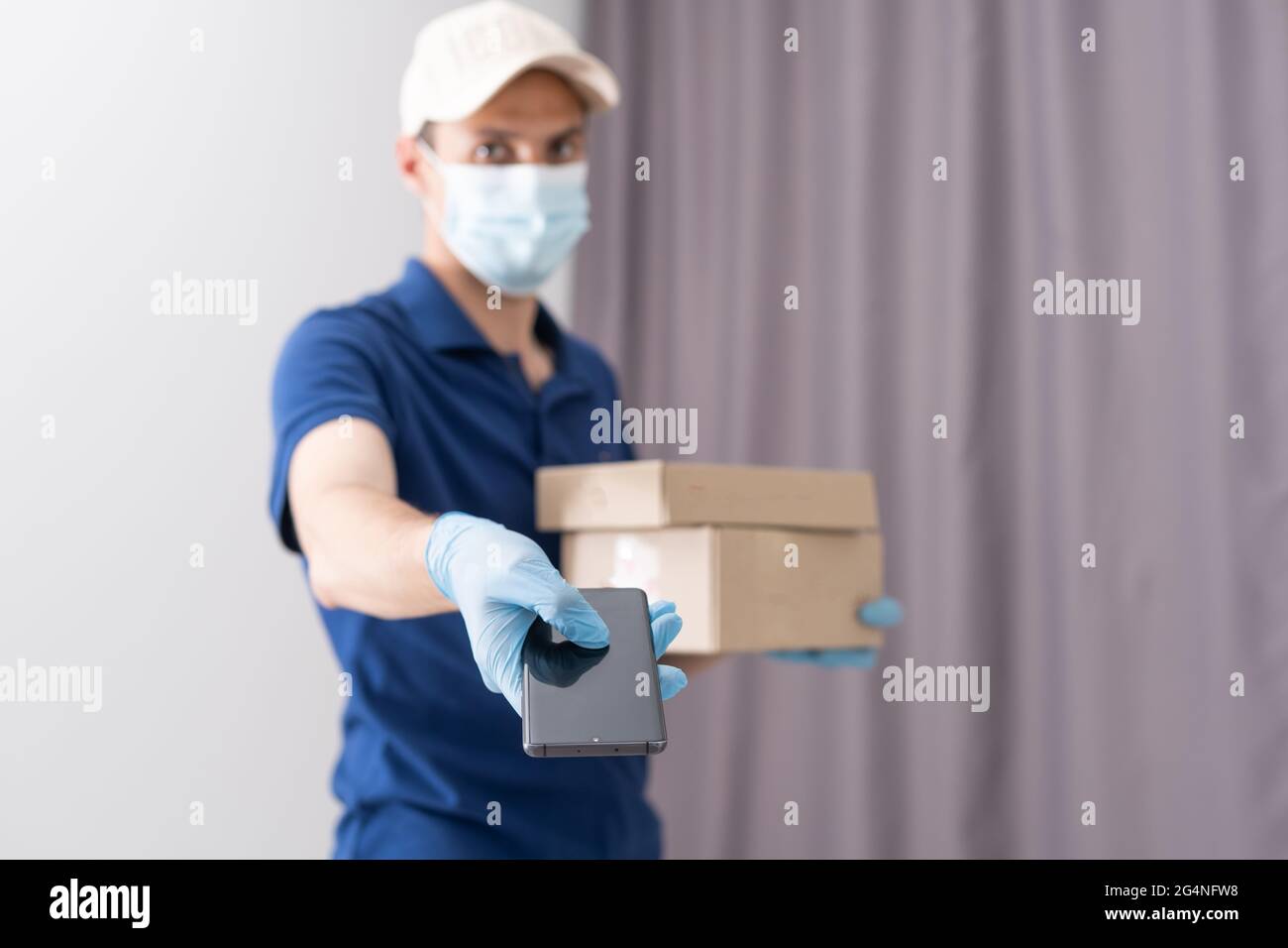 Man from delivery service in t-shirt, in protective mask and gloves ...