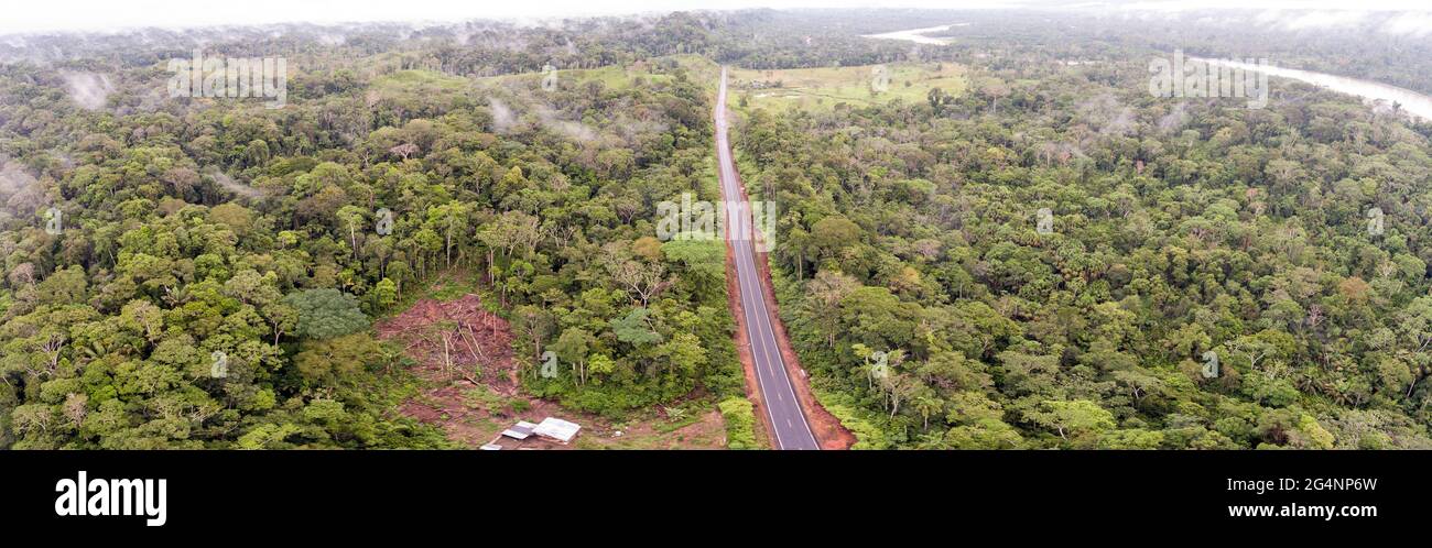 Aerial shot of an Amazonian highway in Ecuador and a clearing made by a subsistence farmer. Roads bring colonization and destruction of the rainforest Stock Photo