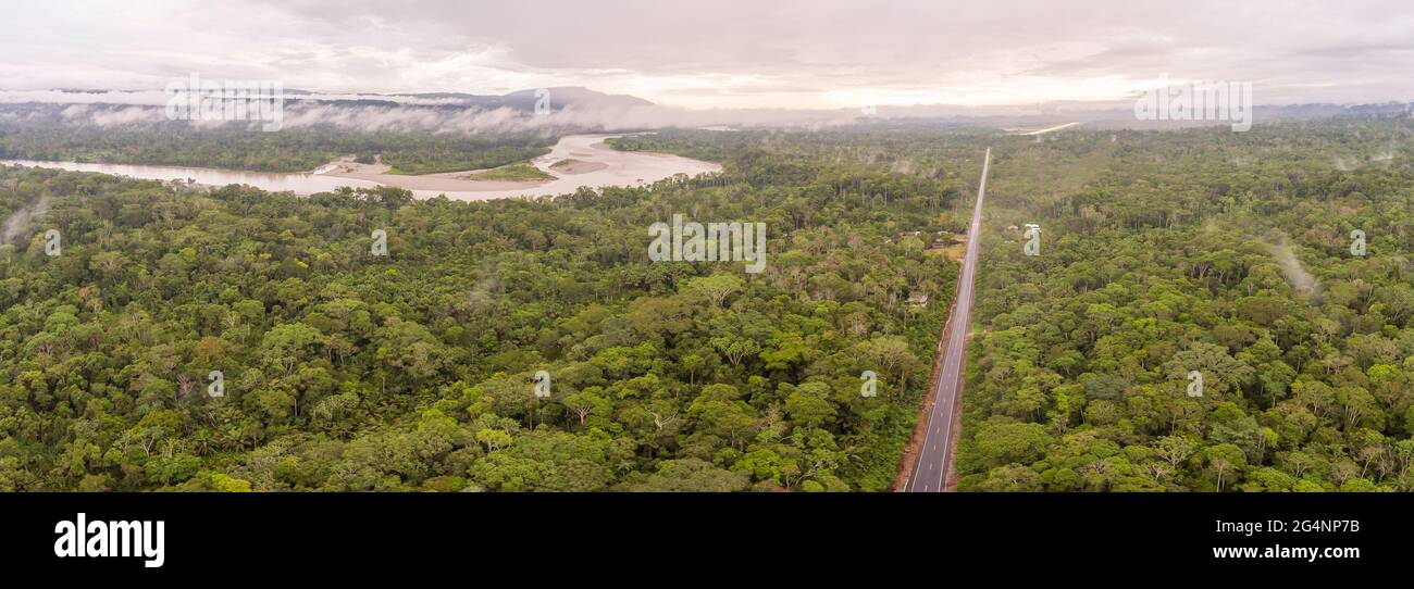 Aerial shot of an Amazonian highway in Ecuador with Rio Napo and Galeras mountain in the background.  Roads bring colonization and destruction of the Stock Photo