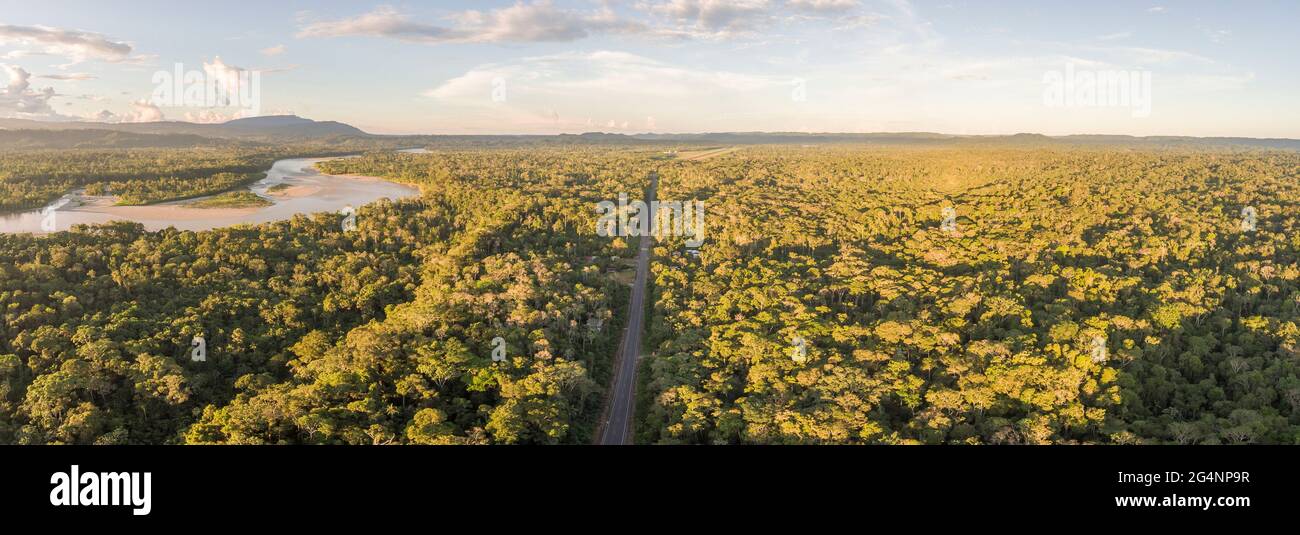 Aerial panorama of an Amazonian highway in Ecuador with Rio Napo and Galeras mountain in the background.  Roads bring colonization and destruction of Stock Photo