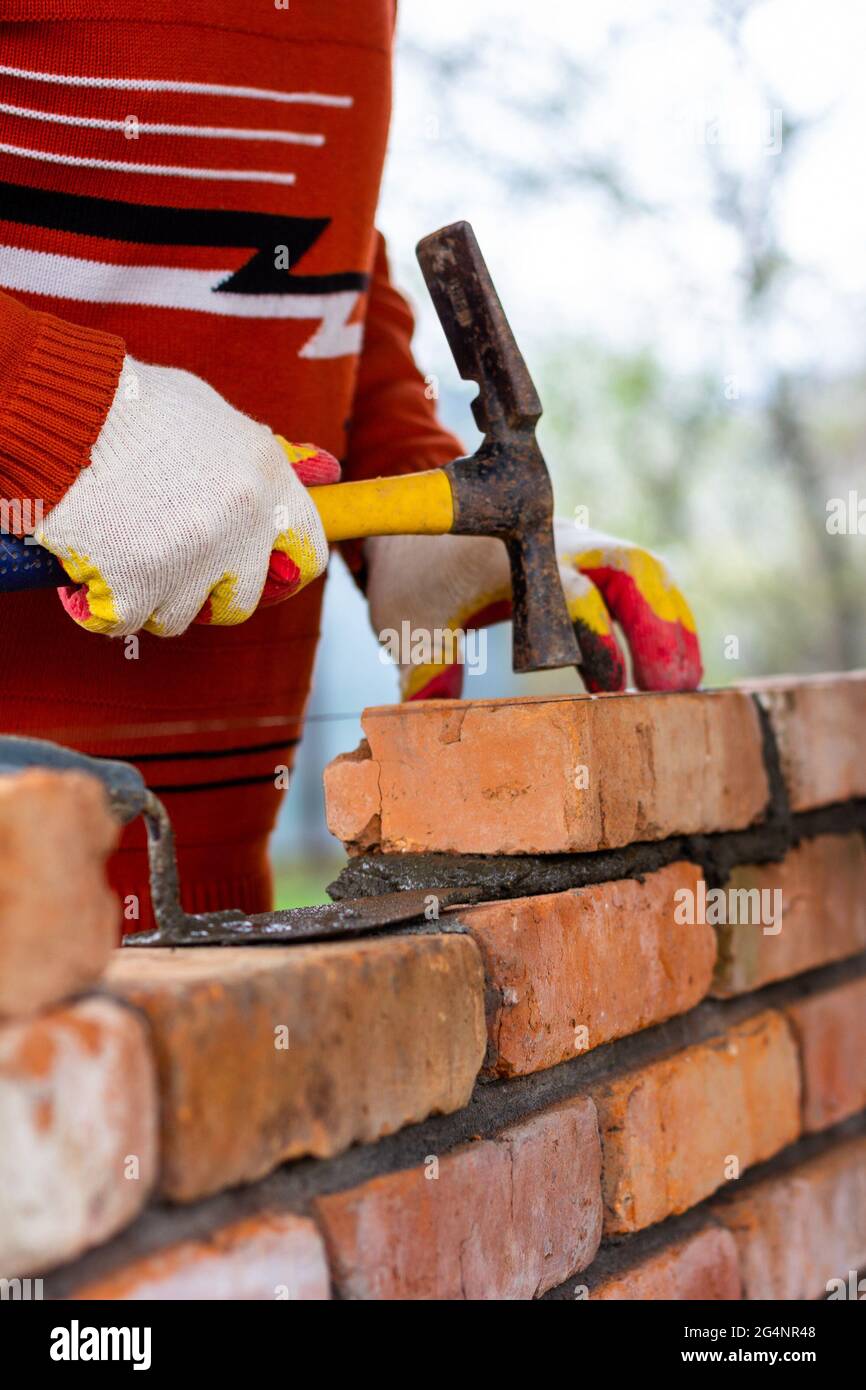 a man builds a brick wall, puts a brick on a cementsand mortar
