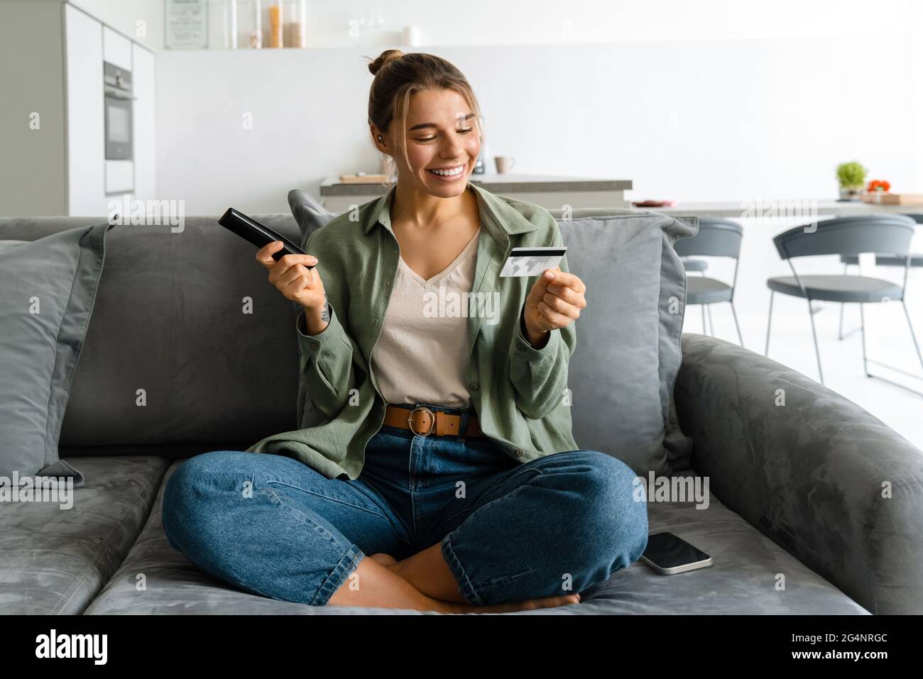 Happy Nice Woman Holding Credit Card While Watching TV With Remote 