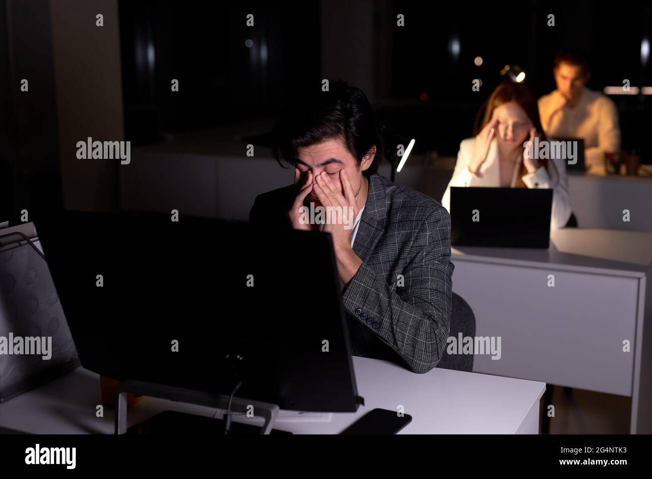 young caucasian tired man in suit sits at night in office
