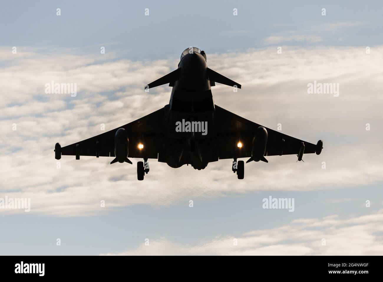 RAF Typhoon silhouetted by the setting sun as it comes into land at RAF Coningsby in Lincolnshire during the summer of 2021. Stock Photo