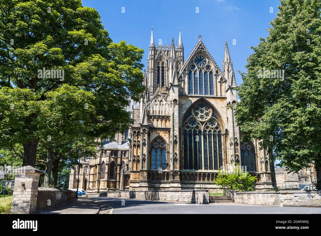 Trees framing Lincoln cathedral pictured under a blue sky in June 2021 ...