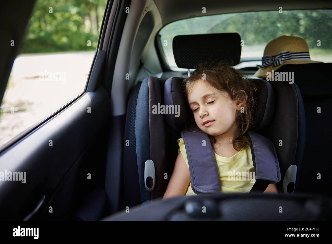 Little girl sleeps in a booster seat in the car. Child safety seat