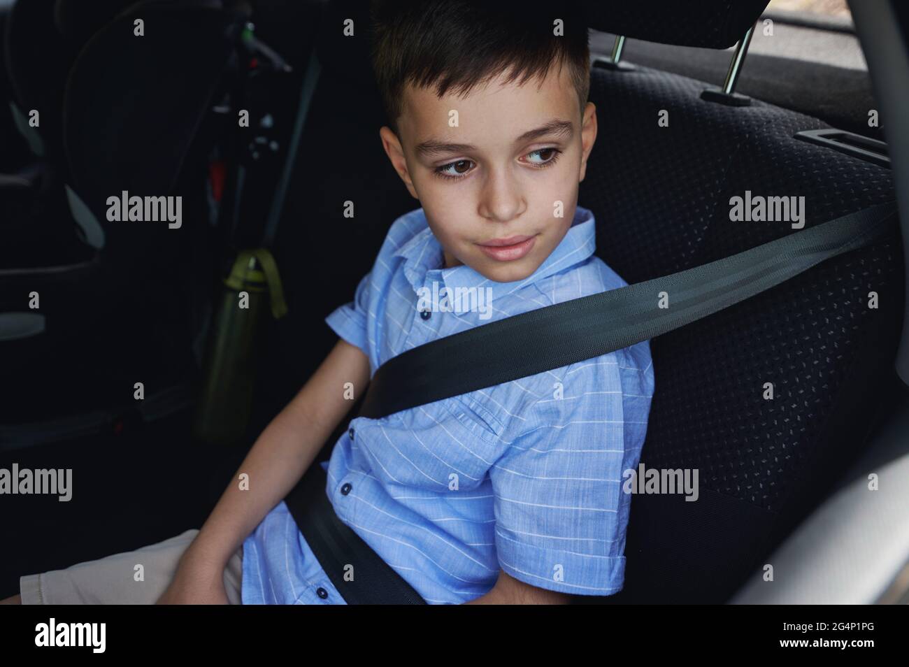 A boy wearing seat belts travels in a protective child car seat. Traveling safely with children. Safe movement of children in the car Stock Photo