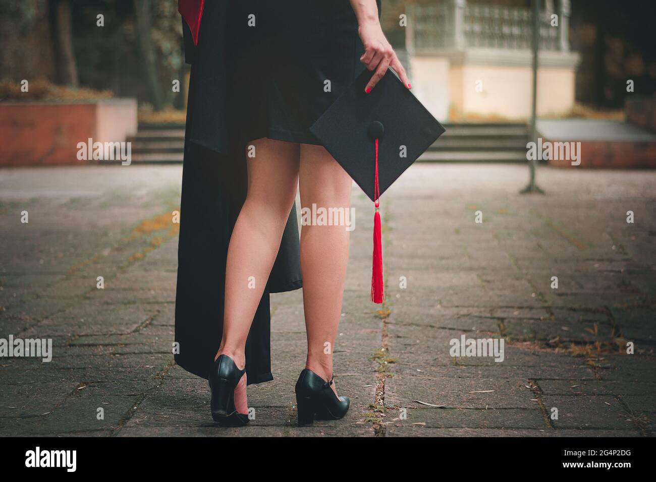 Shot from the back of a graduate, he is walking to attend the graduation ceremony at the university, close-up to the mortarboard in hand, graduation h Stock Photo