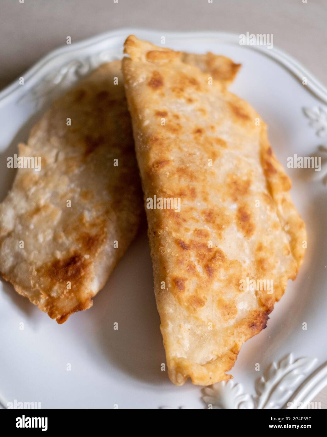 Homemade fried apple pies made from dried apples with flaky pie crust on a white plate. Stock Photo