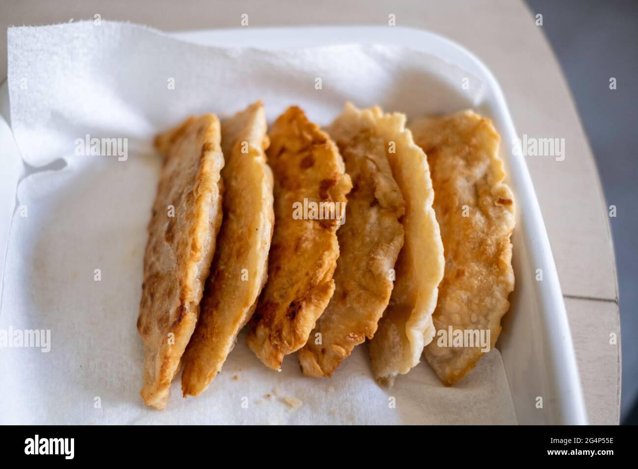 Homemade fried apple pies made from dried apples with flaky homemade pie crust on draining on a paper towel. Stock Photo