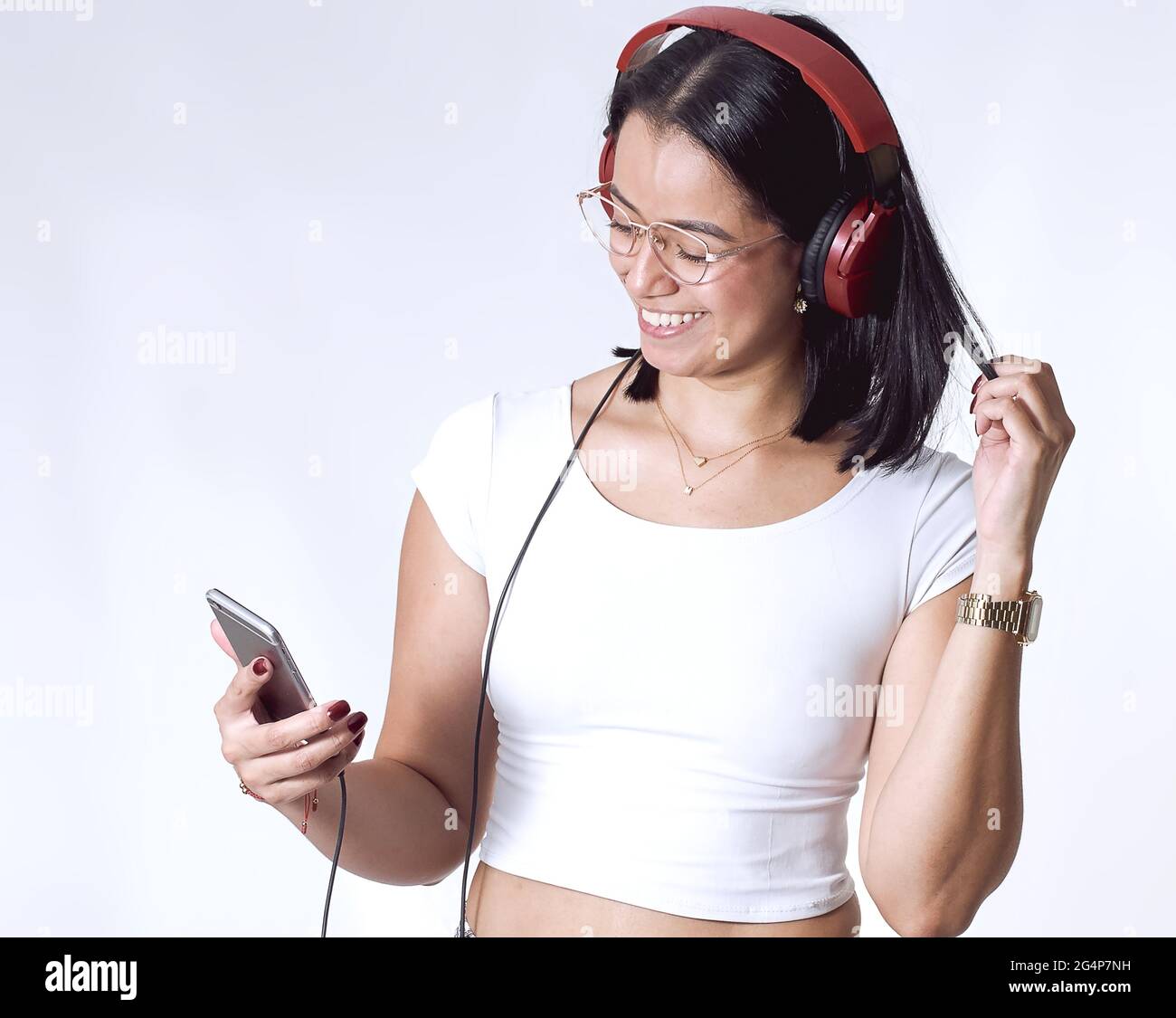 Hispanic female listening to music with headphones isolated on a white ...
