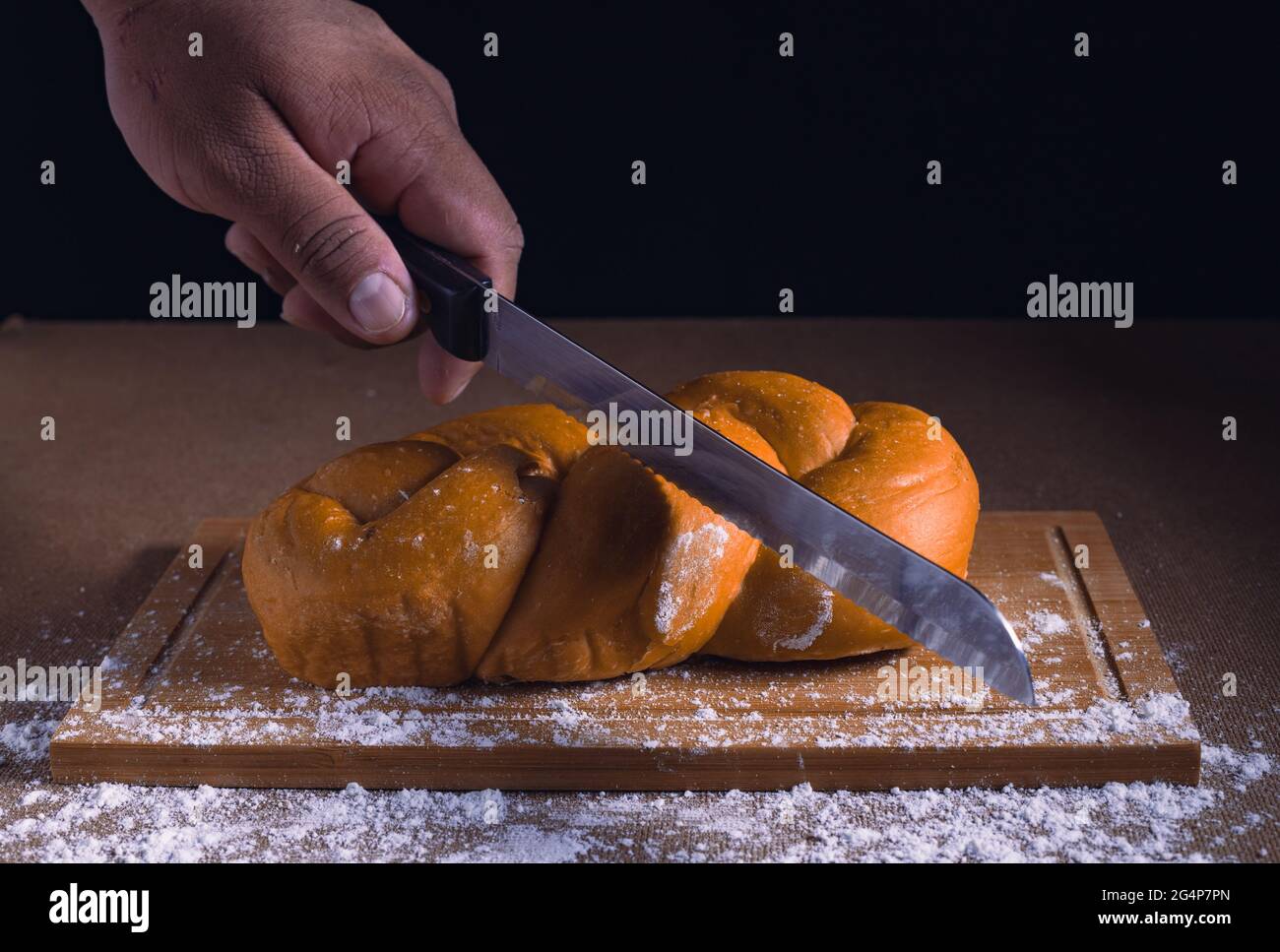 cutting yellow bread on the table with knife Stock Photo