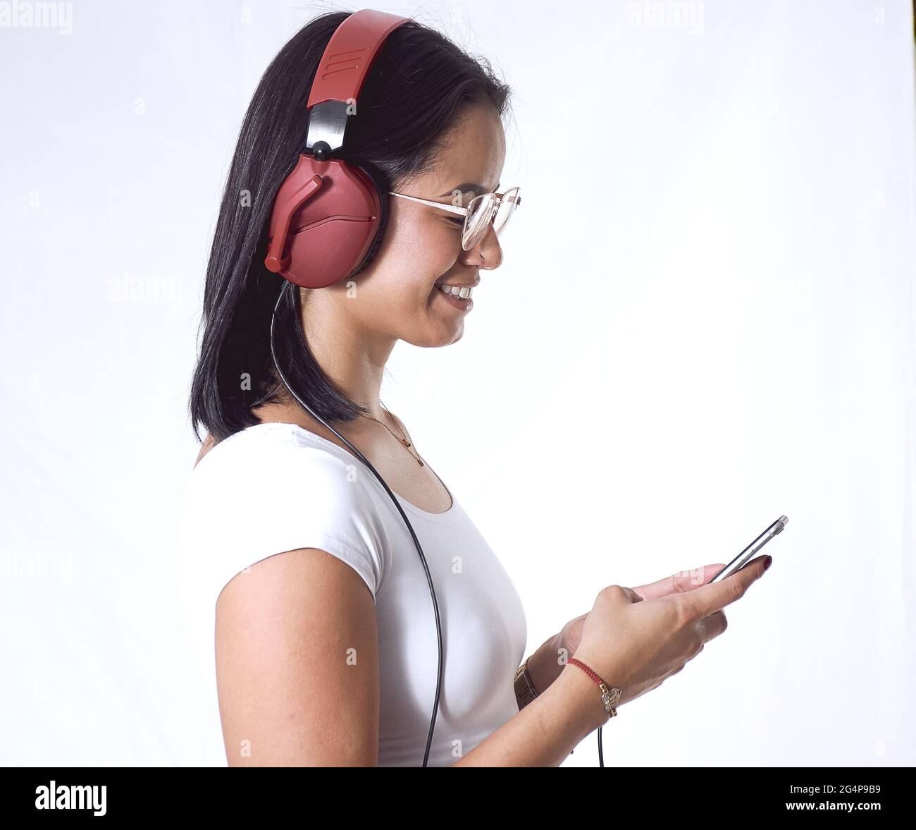 A Hispanic female listening to music with headphones isolated on a ...
