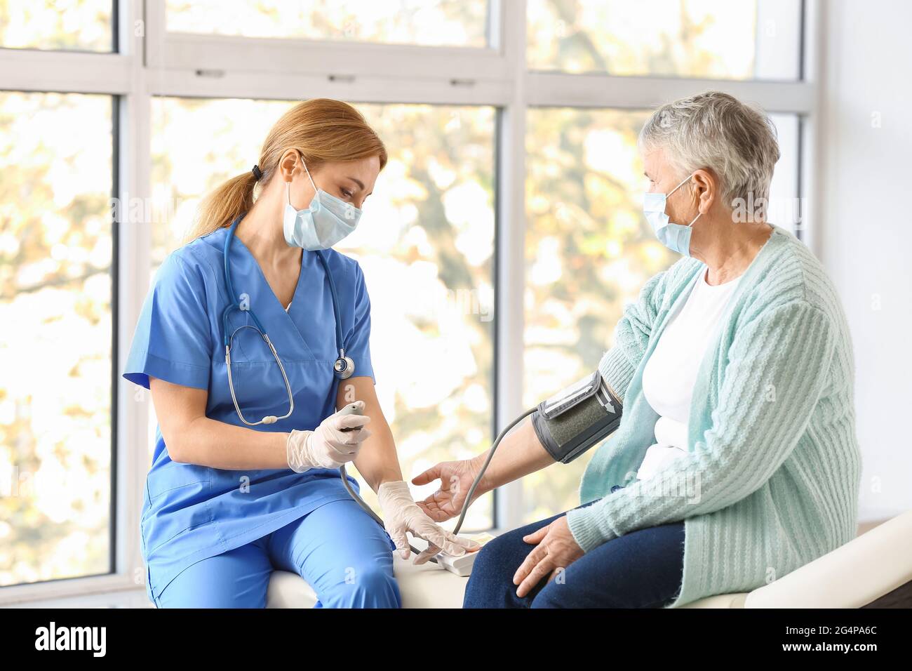 Doctor measuring blood pressure of senior woman in clinic Stock Photo ...