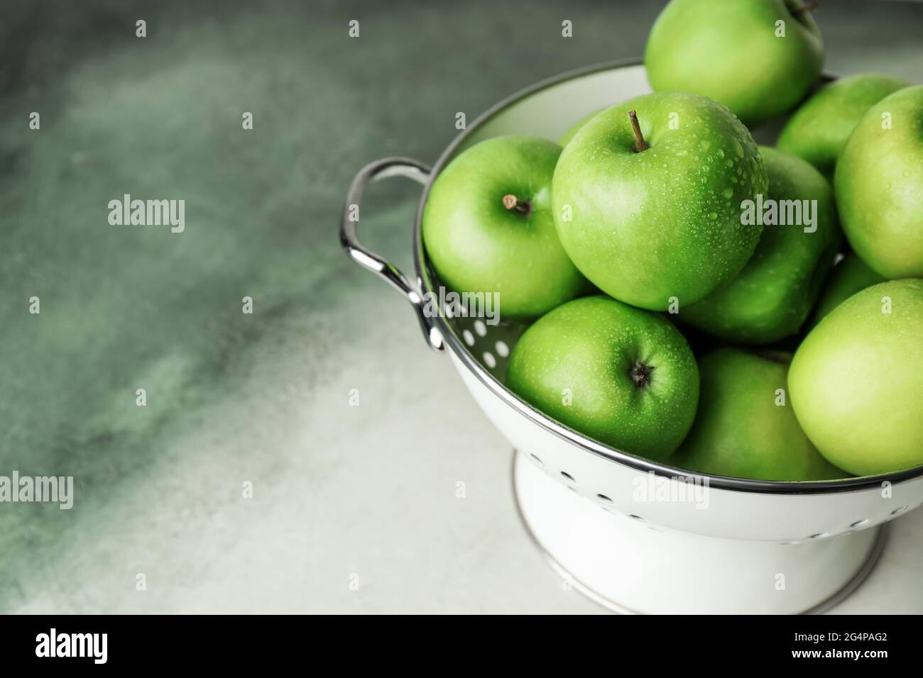 Colander with fresh green apples on color background Stock Photo - Alamy