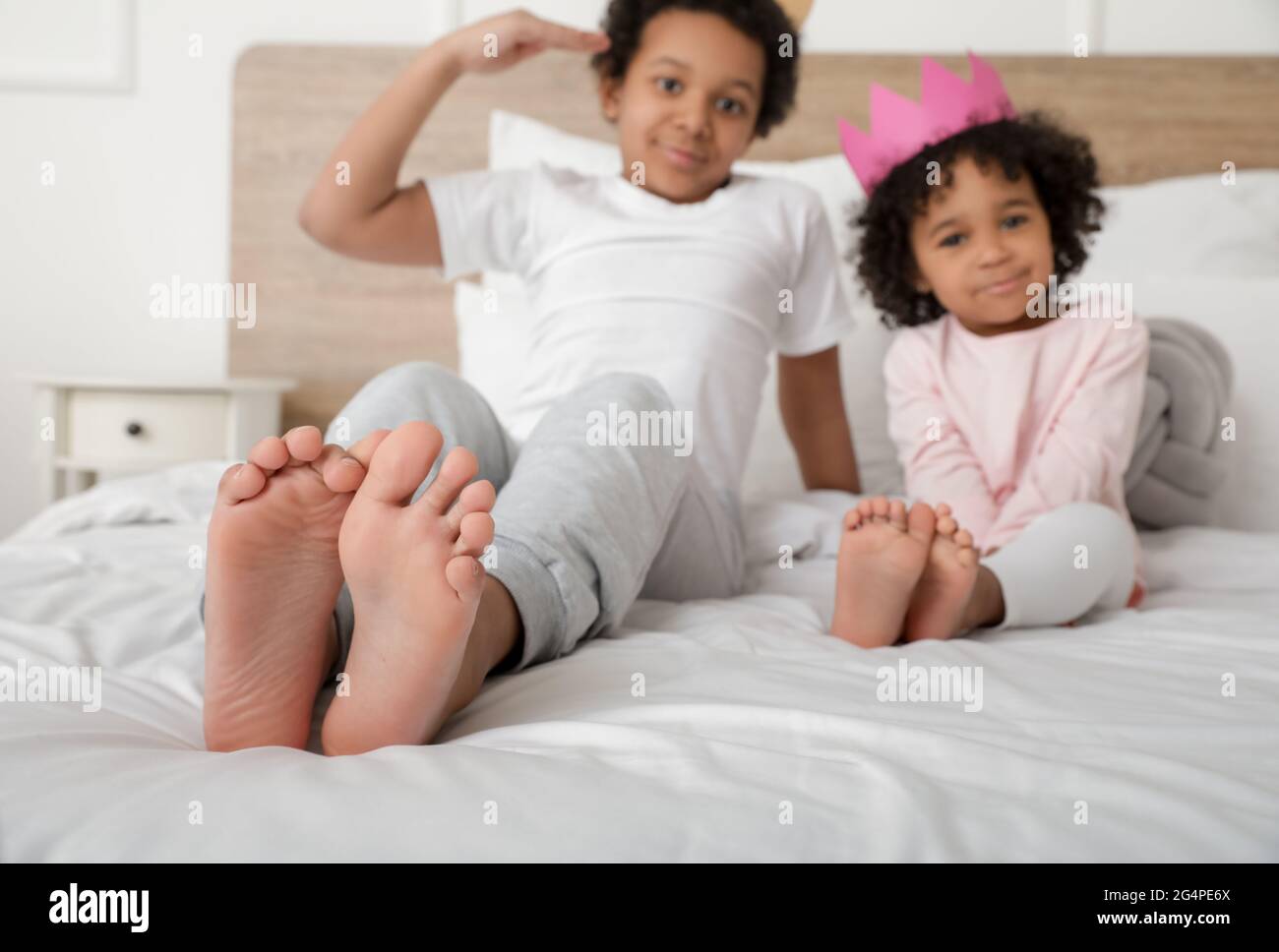 African-American children sitting on bed in room Stock Photo