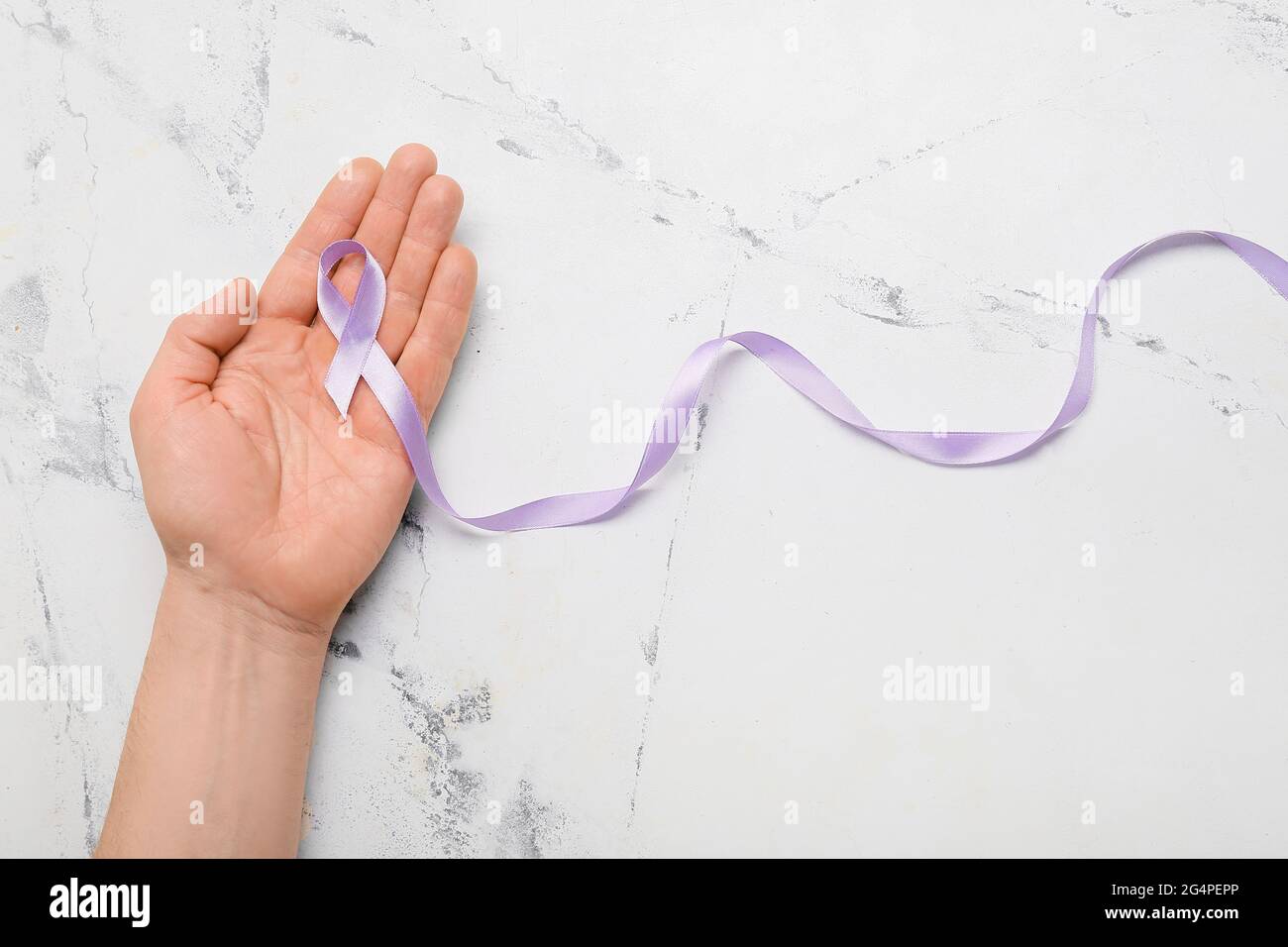 Male hand with lilac ribbon on light background. Cancer awareness concept Stock Photo