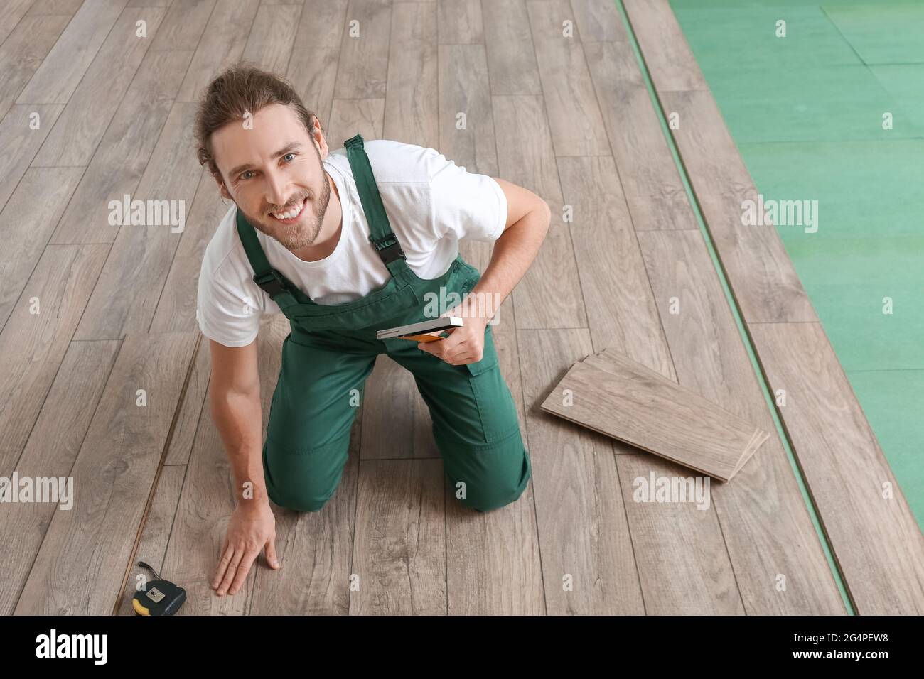 Carpenter installing laminate flooring in room Stock Photo