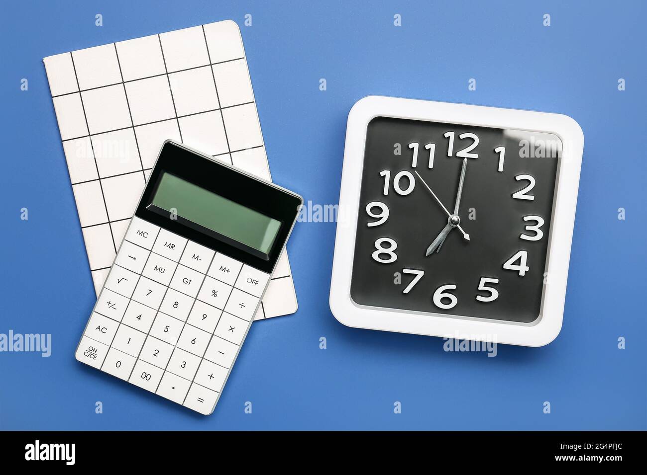 Stylish clock with calculator and notebook on color background Stock ...