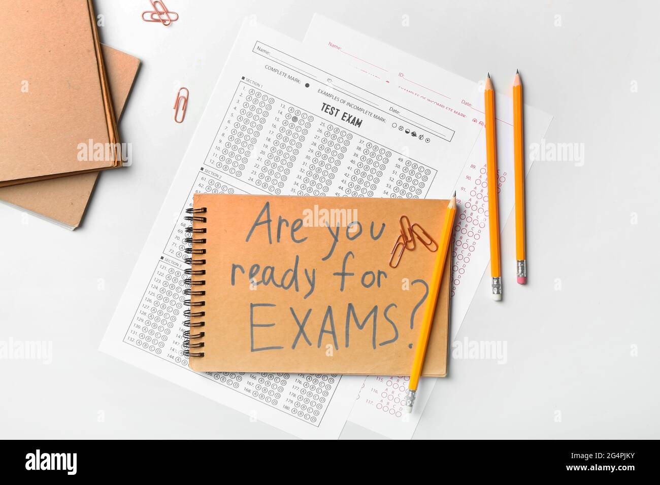 Stationery, answer sheets and notebook with text ARE YOU READY FOR EXAMS? on light background
