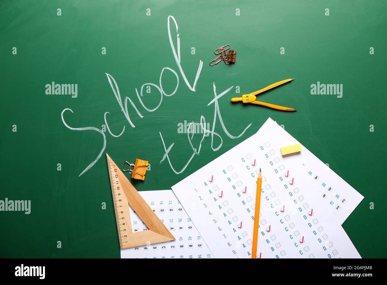 Answer sheets with stationery and text SCHOOL TEST on blackboard Stock Photo