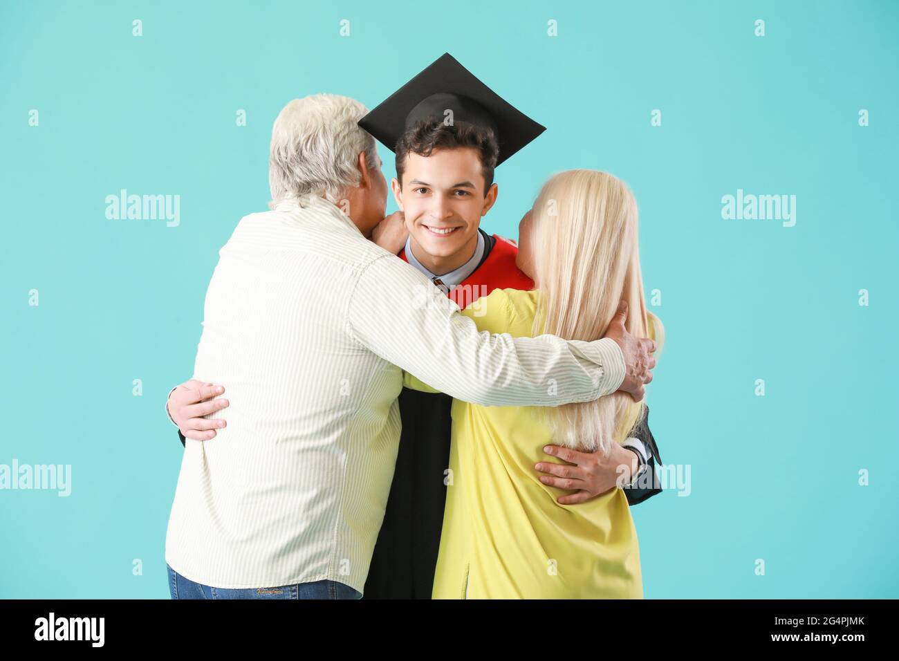 Happy male graduation student with his parents on color background ...
