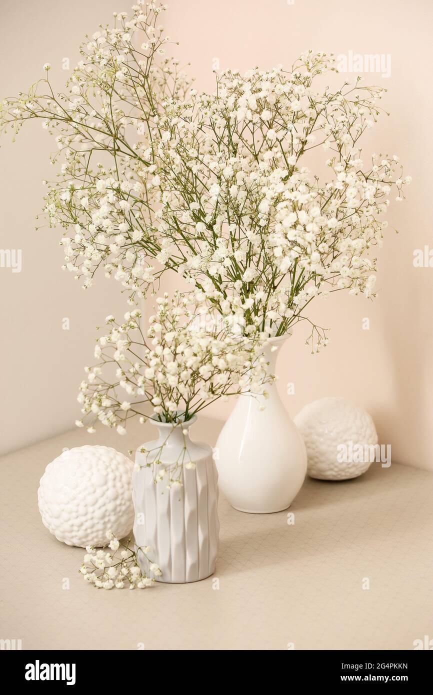 Vases with beautiful gypsophila flowers on table near color wall Stock ...