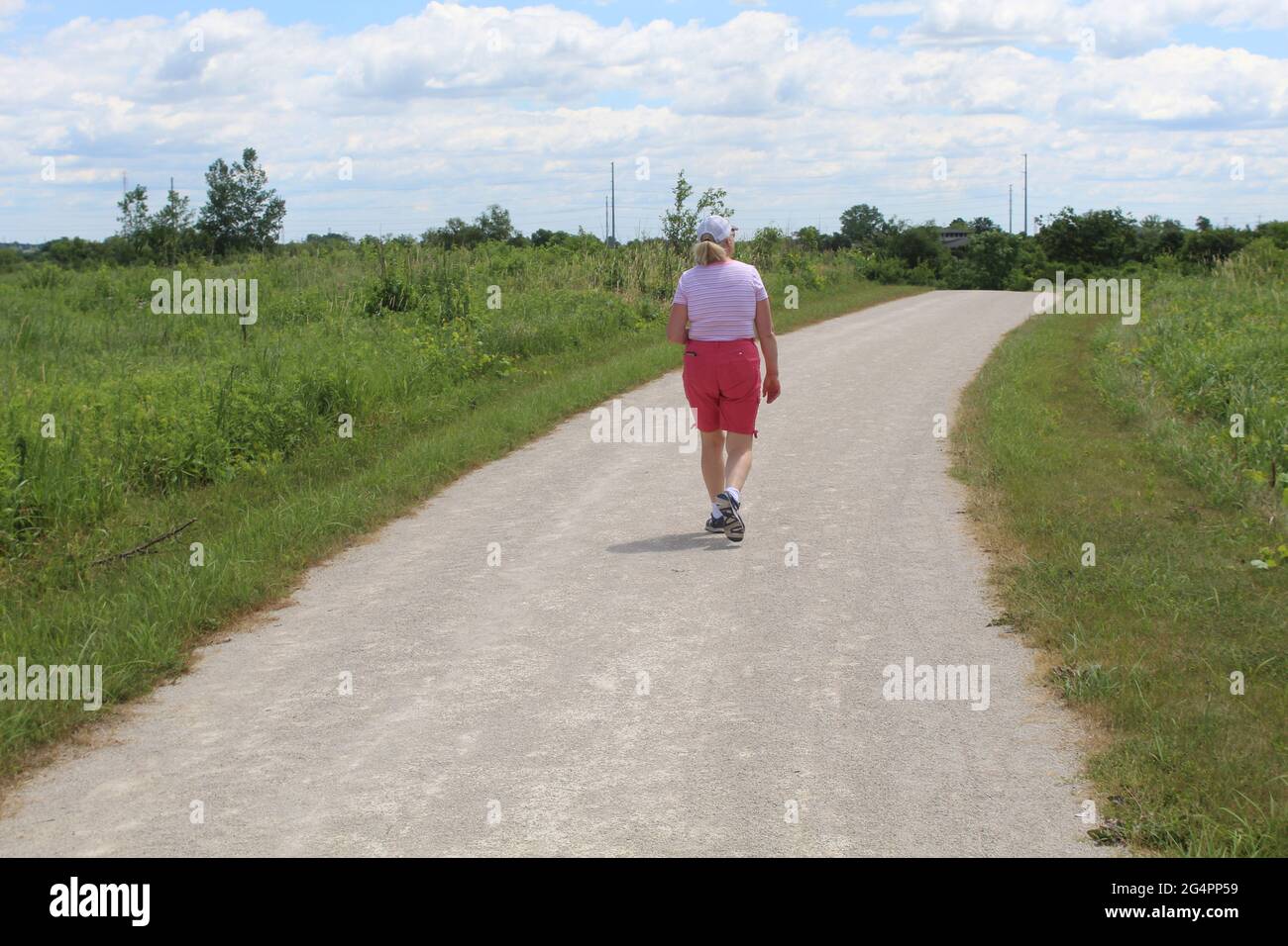 Woman in pink walking on a trail in summer at James 'Pate' Philip State Park in Bartlett, Illinois Stock Photo