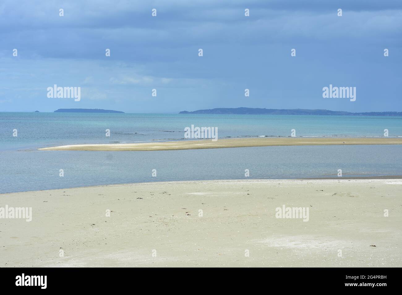 Patch of sand in calm sea close to flat sandy beach exposed at low tide. Stock Photo