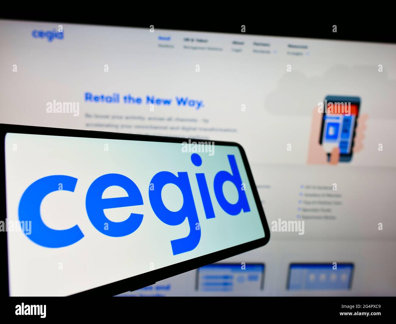 Smartphone with logo of French ERP software development company Cegid SA on screen in front of website. Focus on center-right of phone display. Stock Photo