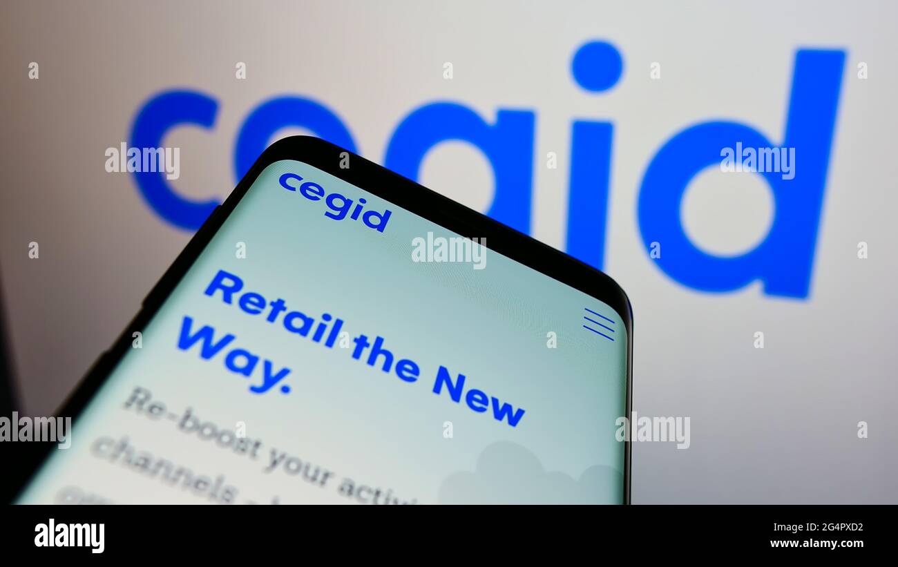Mobile phone with website of French ERP software company Cegid SA on screen in front of business logo. Focus on top-left of phone display. Stock Photo
