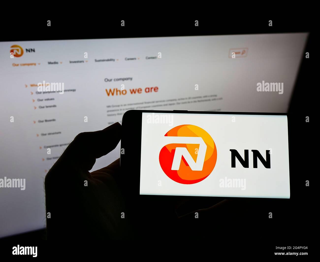 Person holding smartphone with logo of Dutch insurance company NN Group N.V. on screen in front of website. Focus on phone display. Stock Photo