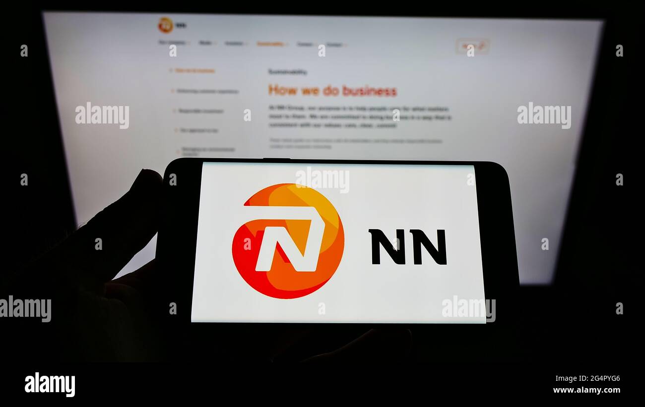 Person holding cellphone with logo of Dutch insurance company NN Group N.V. on screen in front of business webpage. Focus on phone display. Stock Photo