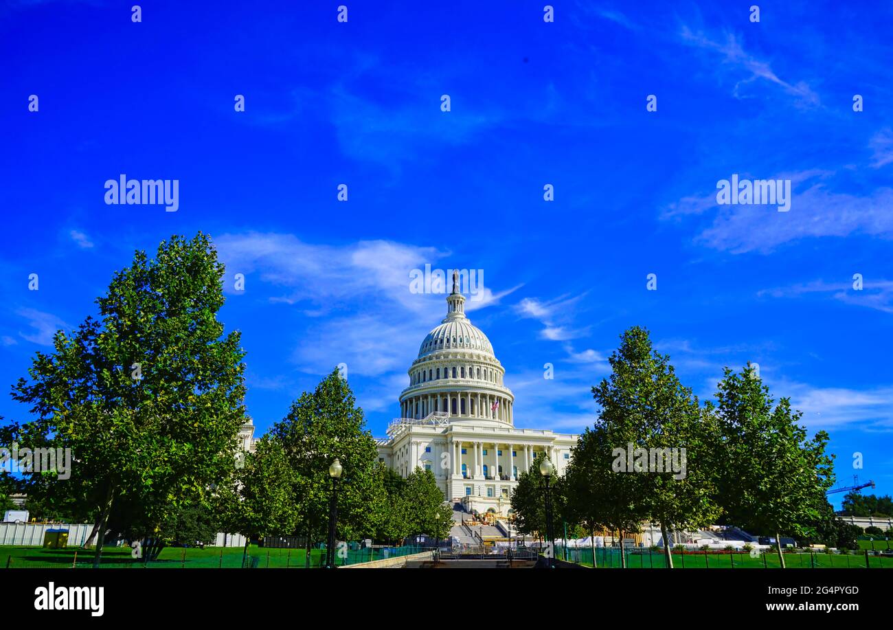 The white Capital building with a dome, green trees and blue sky.Famous buildings in Washington, D.C., U.S.A. October 2016. Stock Photo