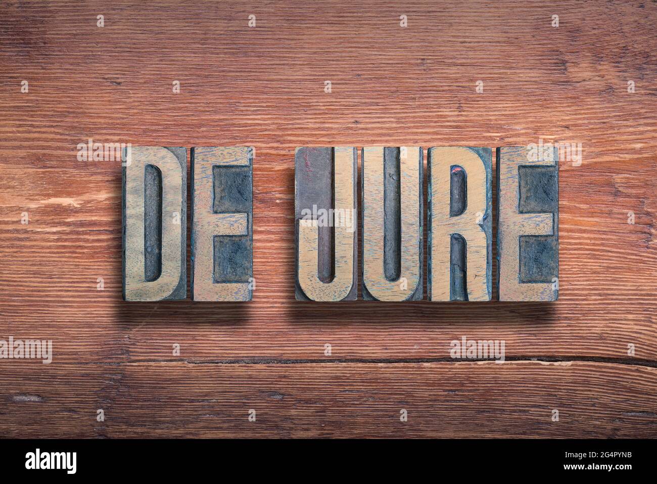 de jure ancient Latin saying meaning «something established by law» combined on vintage varnished wooden surface Stock Photo