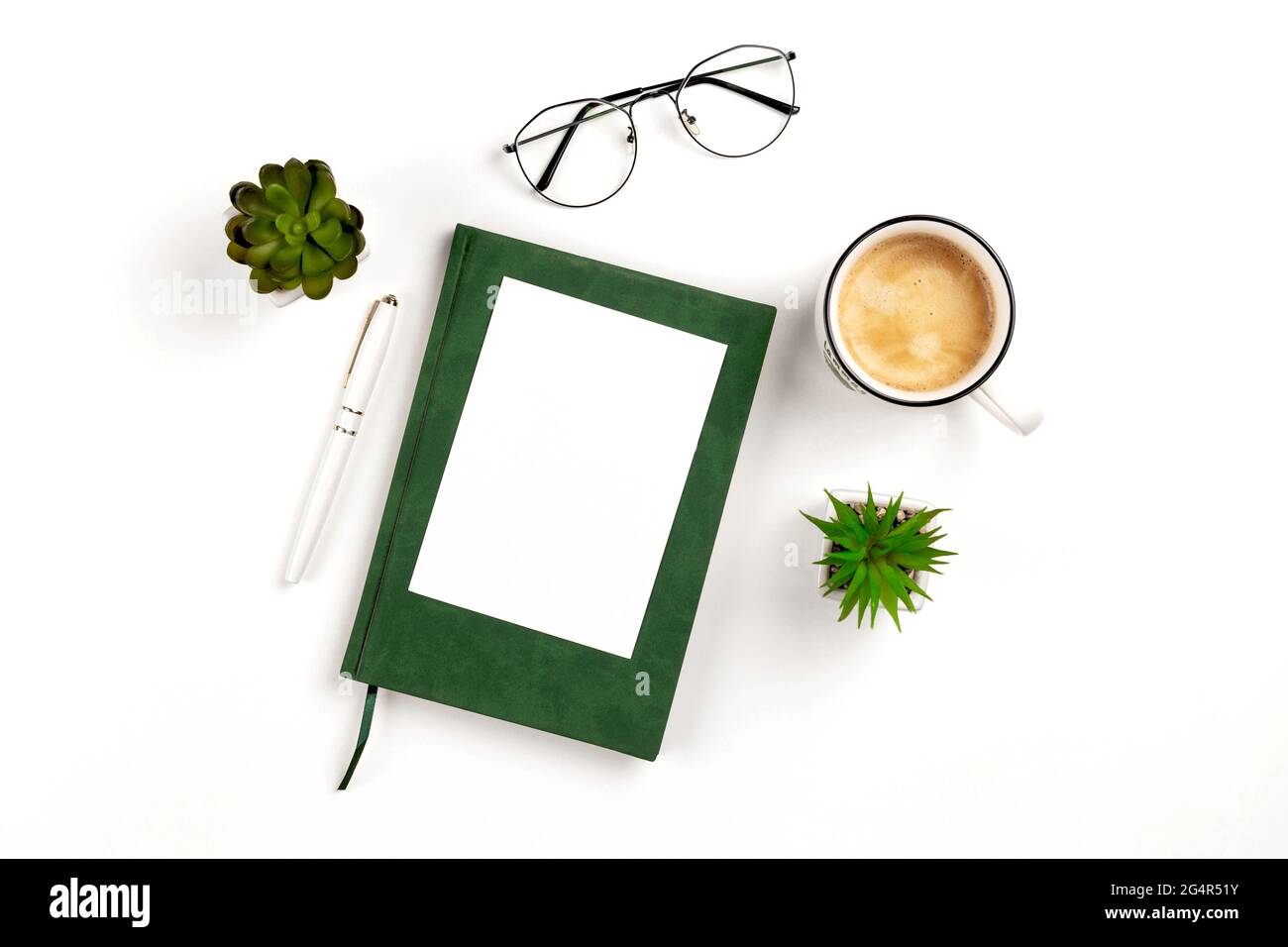 Light postcard mockup for design presentation on a white workplace with coffee, notebook, pen, glasses and potted flowers. Stock Photo