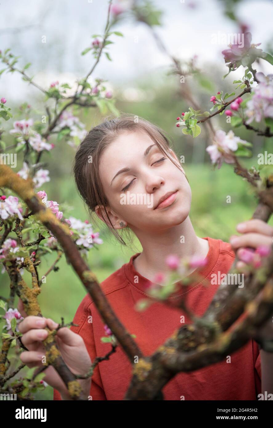 A young girl in a blooming garden looks at flowering trees Stock Photo ...