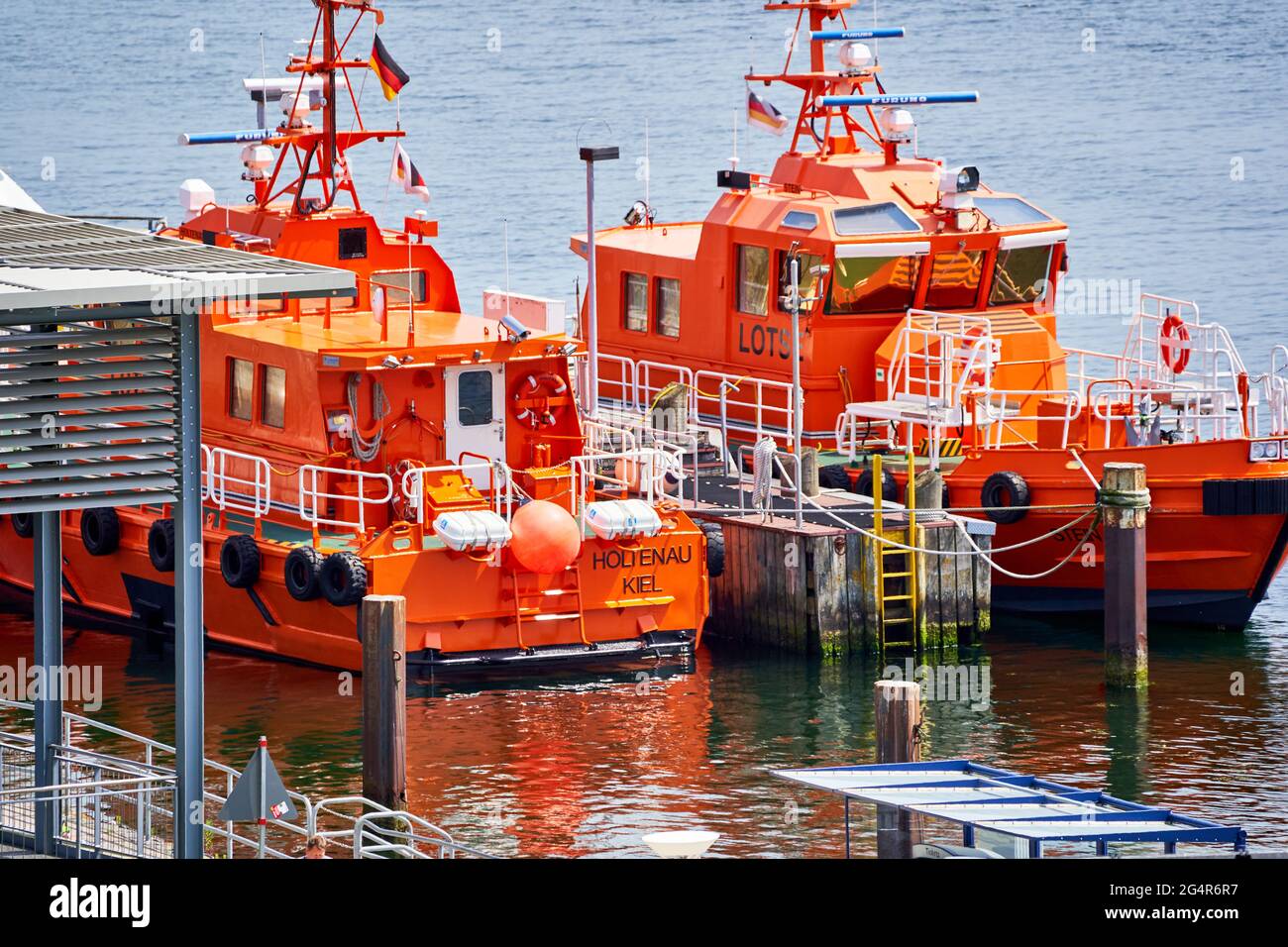 Lifeboat and pilot boat in red luminous paint wait at the pier for their deployment in the Baltic Sea, Travemunde, Germany, June 10., 2021 Stock Photo