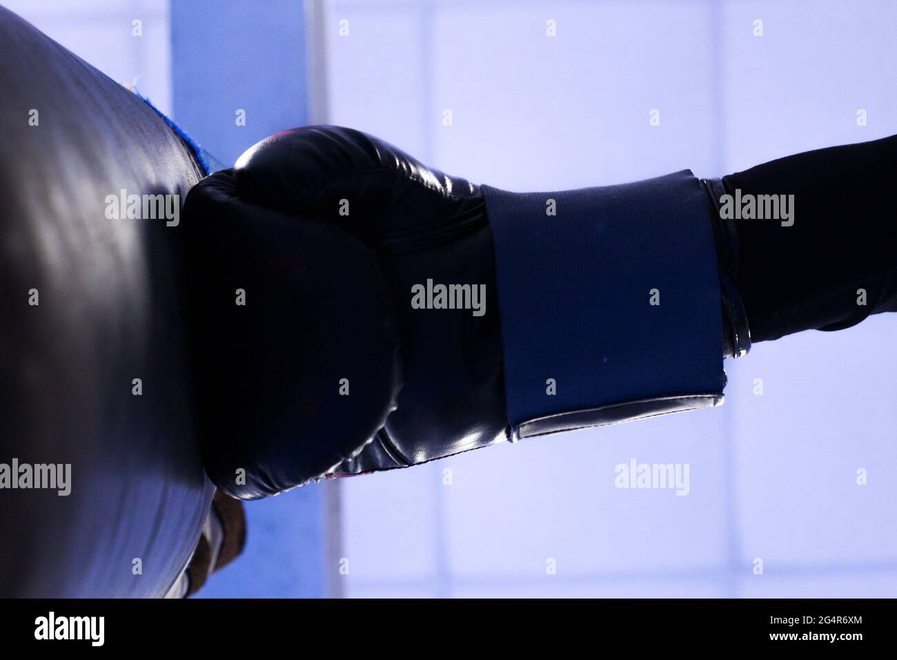 Low angle of a boxing glove hitting a punching bag under a blurred