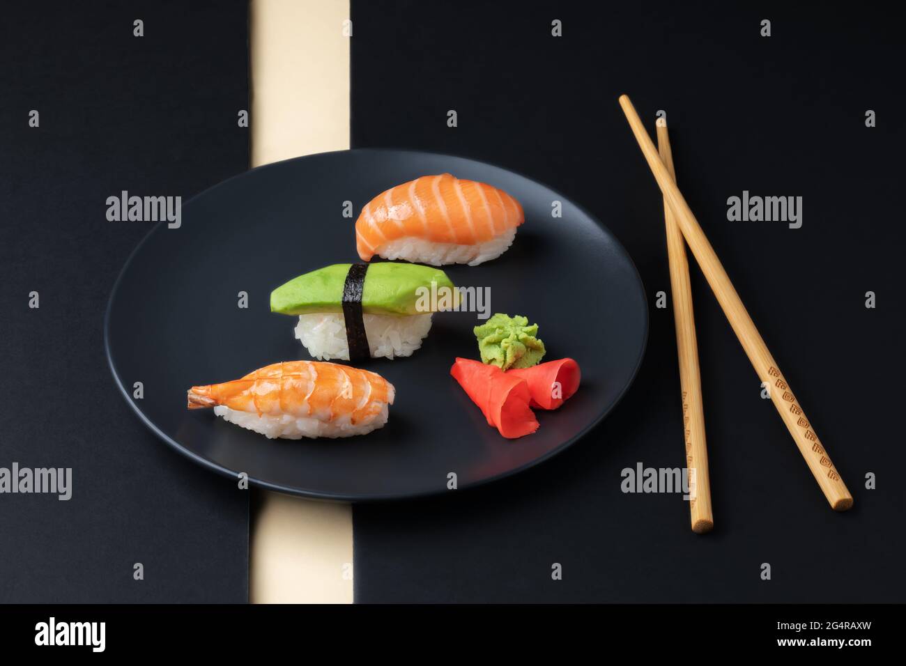 Japanese cuisine - set of nigiri sushi with salmon, avocado and shrimp on a black plate with chopsticks. Stock Photo