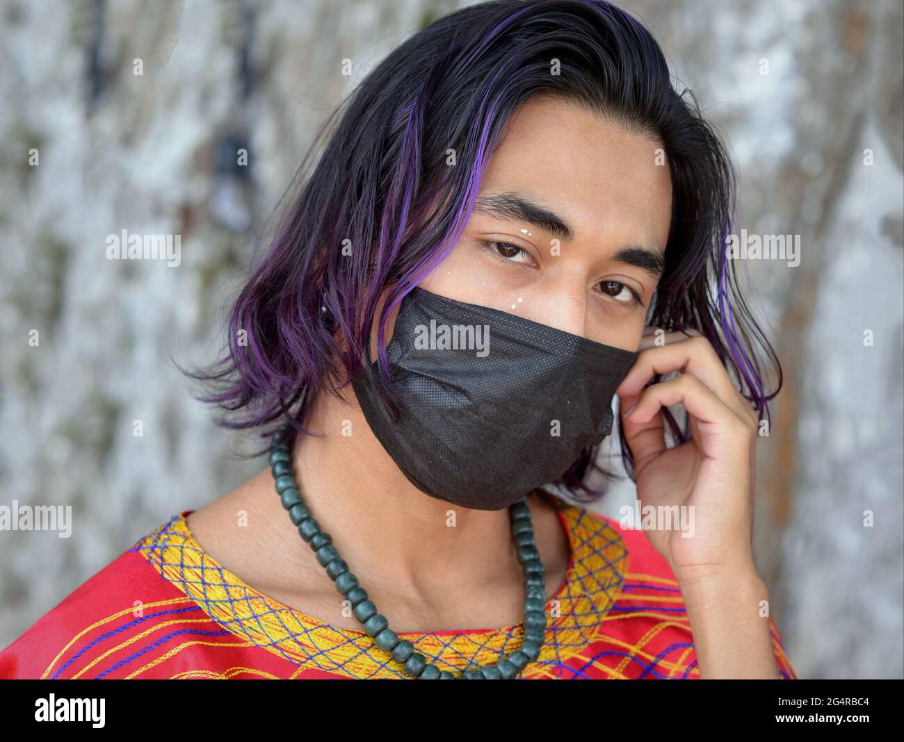 Handsome young Mexican man with a blue purple dyed hair streak wears a  black face mask during the global coronavirus pandemic and looks at the  camera Stock Photo - Alamy